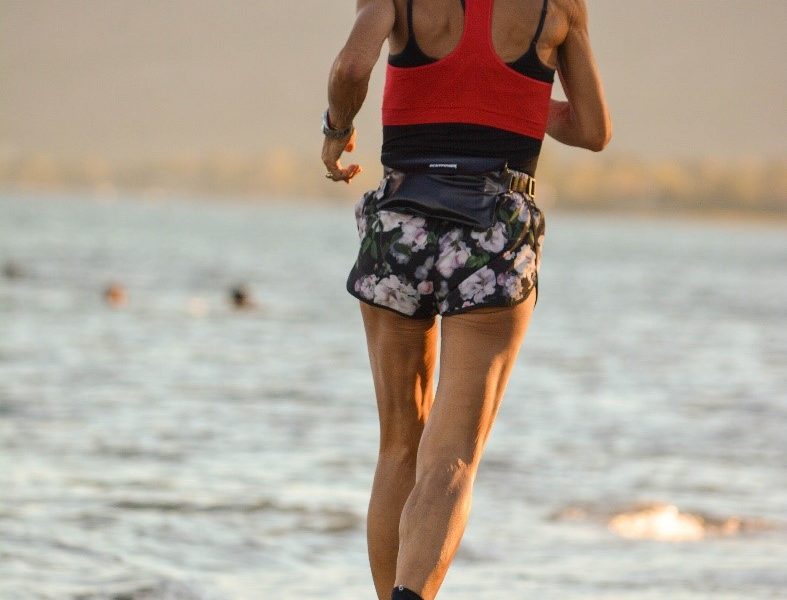 A woman running on a beach near Lane Cove Physio